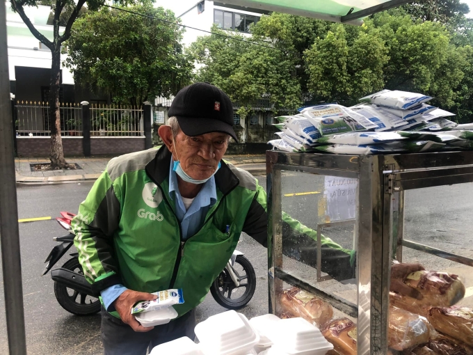 Một người đàn ông chạy xe ôm đến lấy bánh mì, sữa tại tủ bánh mì 0 đồng trên đường Quang Trung, quận Hải Châu vào một sáng hồi tháng cuối năm 2021. Ảnh: Nhân vật cung cấp