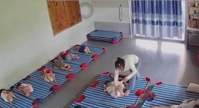 Cảnh cô giáo dốc ngược chân một bé gái, rồi đánh. Ảnh: Cắt từ video